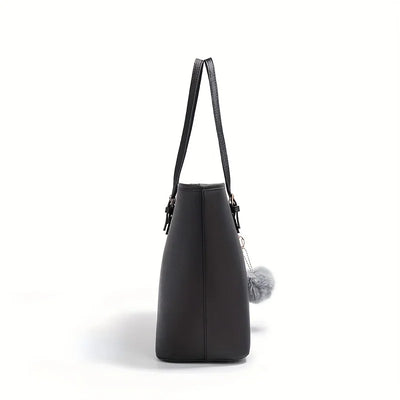 Sac à main noir élégant en cuir avec pompon gris, vue latérale. Accessoire mode femme, design moderne et chic. Idéal pour toutes occasions.