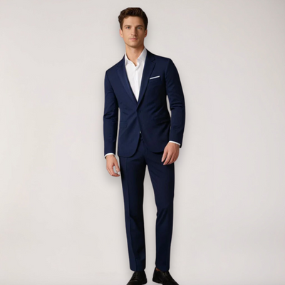 Homme en costume bleu marine élégant, chemise blanche, chaussures noires, pose debout. Mode masculine, tenue formelle, style classique.