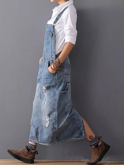 Personne portant une robe salopette en jean décontractée, chemise blanche, bottines marron, marchant sur un sol en bois. Mode urbaine, style décontracté.