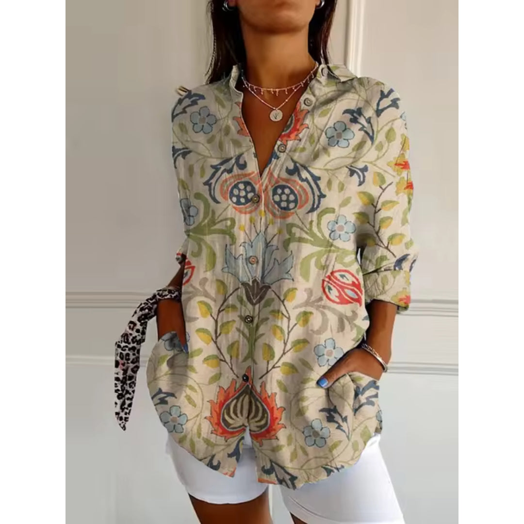 Chemise bohème à motifs floraux colorés, manches longues retroussées, portée par une femme. Style décontracté, tendance mode féminine.