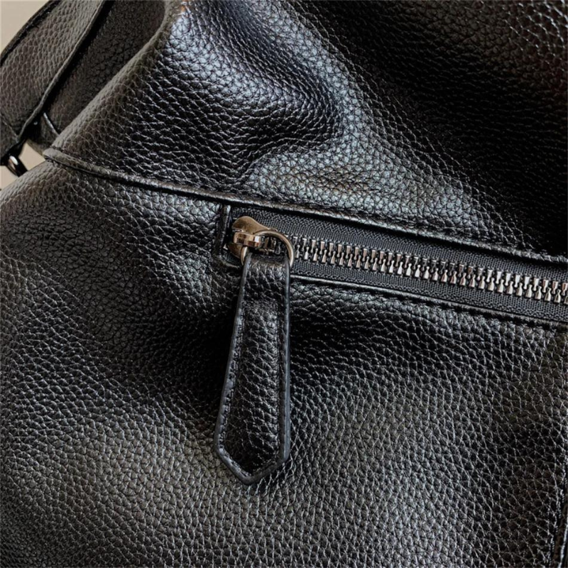 Sac à main en cuir noir texturé avec fermeture éclair argentée, gros plan. Accessoire de mode élégant et tendance pour femmes.