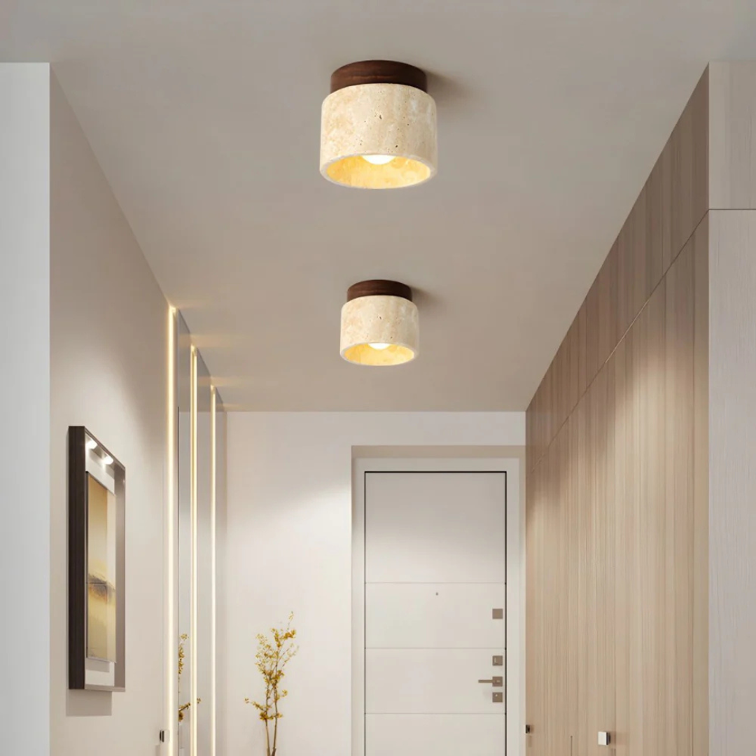 Plafonnier moderne en marbre beige dans un couloir élégant avec murs en bois et porte blanche, éclairage intérieur design contemporain.