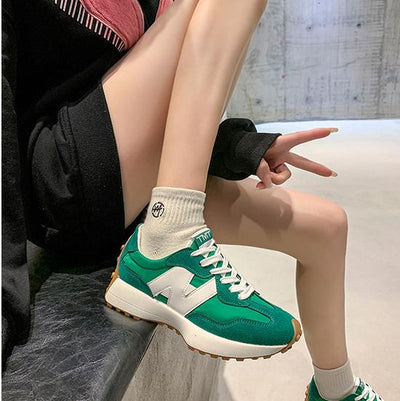 Chaussures de sport vertes et blanches sur fond urbain, portées avec des chaussettes blanches. Style moderne et tendance pour la mode urbaine.
