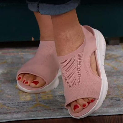 Sandales roses en maille respirante avec semelle blanche, portées par une personne. Chaussures confortables, idéales pour l'été et la marche.