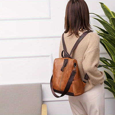 Femme portant un sac à dos en cuir marron, design élégant, intérieur spacieux, idéal pour le travail ou les voyages. Accessoire mode tendance.