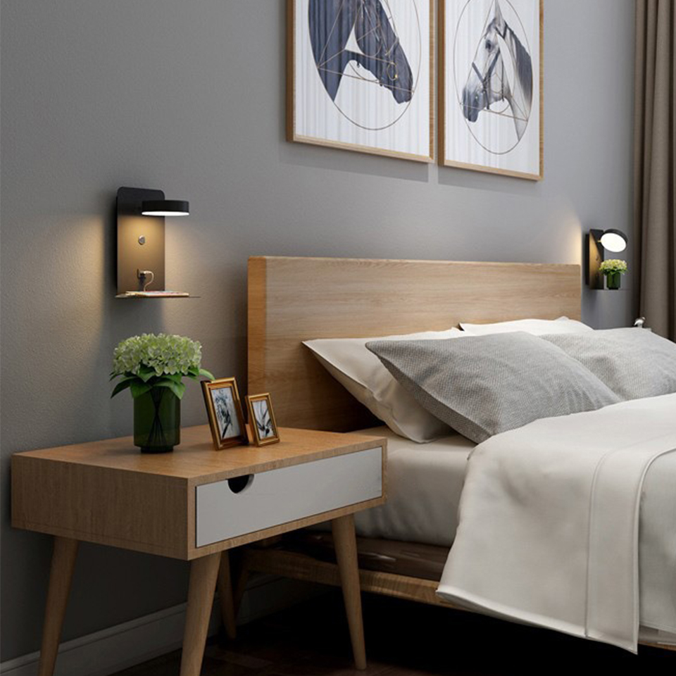Chambre moderne avec lit en bois clair, table de chevet, lampes murales noires, tableaux de chevaux et plante verte. Décoration intérieure élégante.