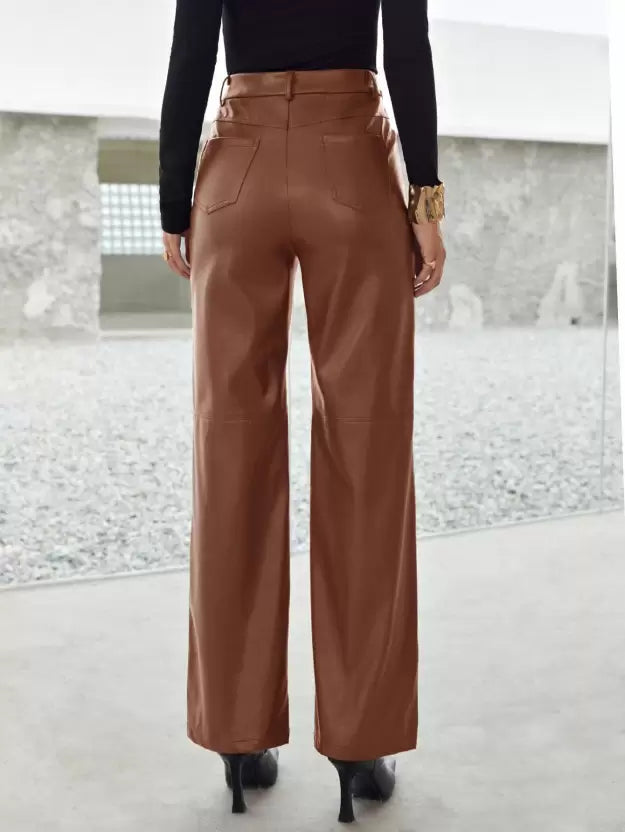 Femme portant un pantalon en cuir marron, vue de dos, avec des talons noirs et un haut noir, dans un environnement moderne et minimaliste.