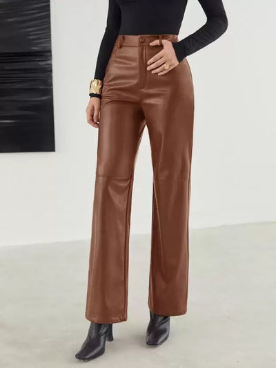 Pantalon en cuir marron pour femme, taille haute, coupe évasée, porté avec un haut noir à manches longues et des bottines noires.