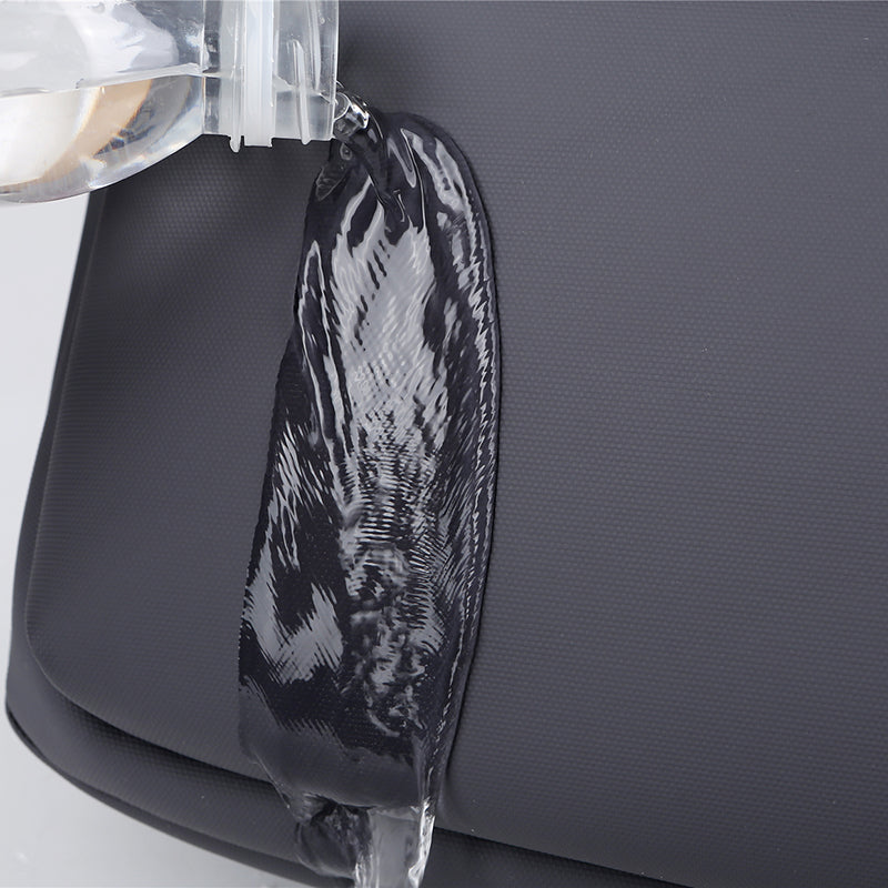 Sac à dos imperméable noir avec eau versée, démontrant sa résistance à l'eau. Accessoire idéal pour voyage, randonnée, usage quotidien.