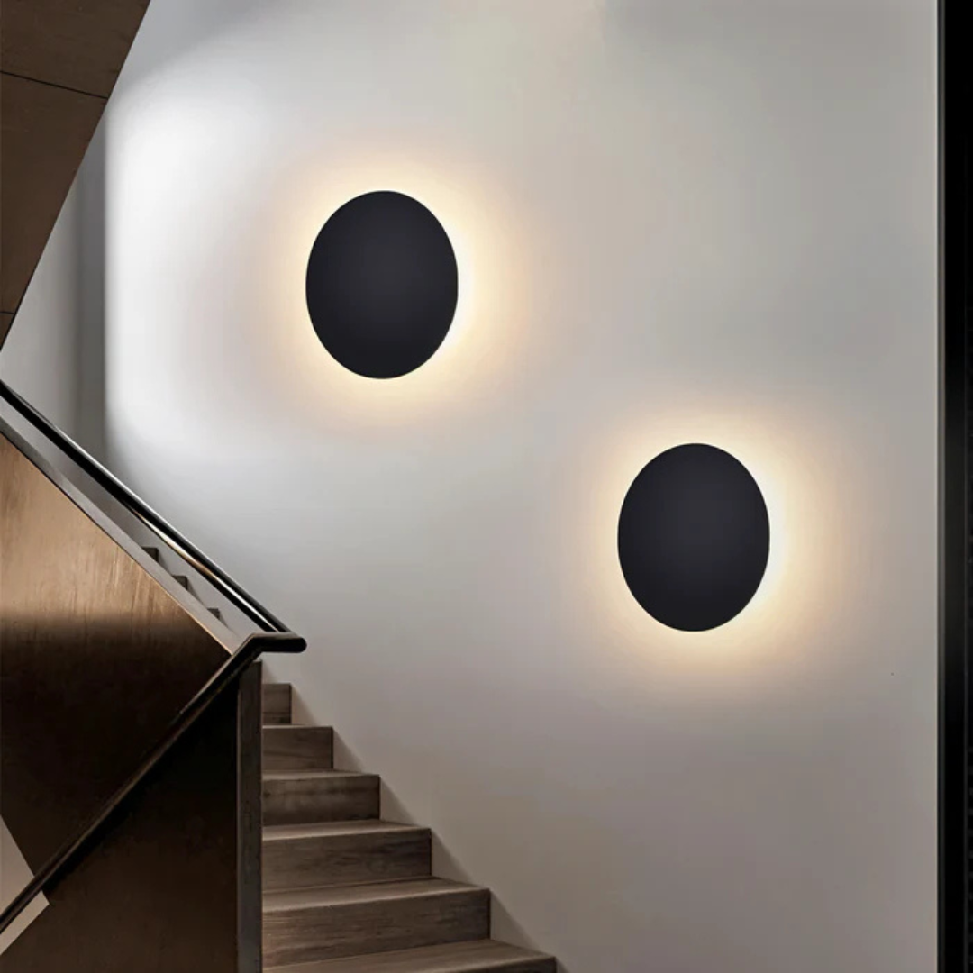 Appliques murales rondes noires modernes éclairant un escalier en bois, design minimaliste, intérieur contemporain, éclairage d'ambiance élégant.