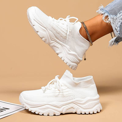 Baskets blanches modernes avec semelle épaisse, portées avec un jean déchiré. Chaussures de sport tendance pour femme, style décontracté et urbain.