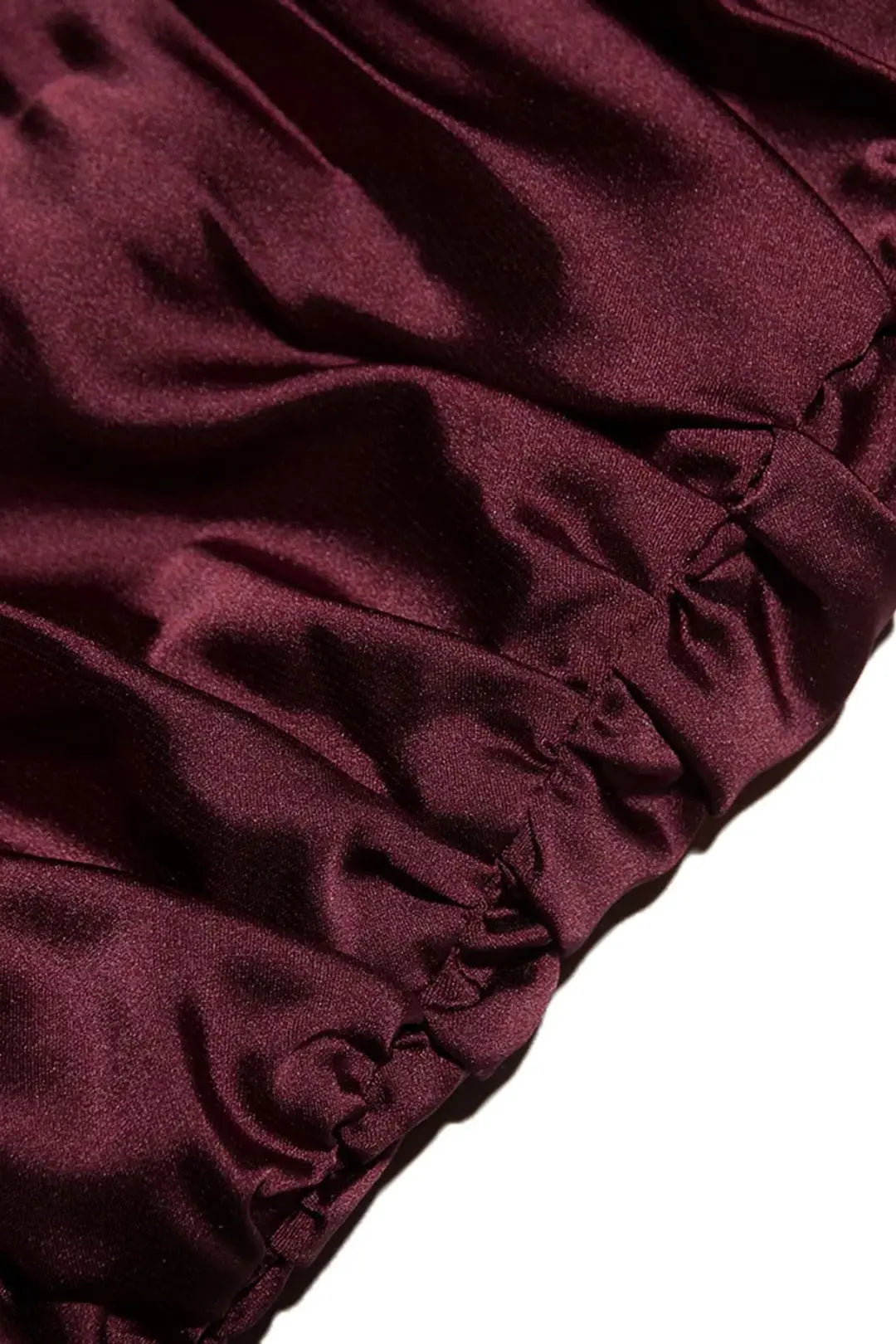 Tissu satin bordeaux plissé, texture lisse et brillante, gros plan. Idéal pour mode, couture, décoration intérieure.