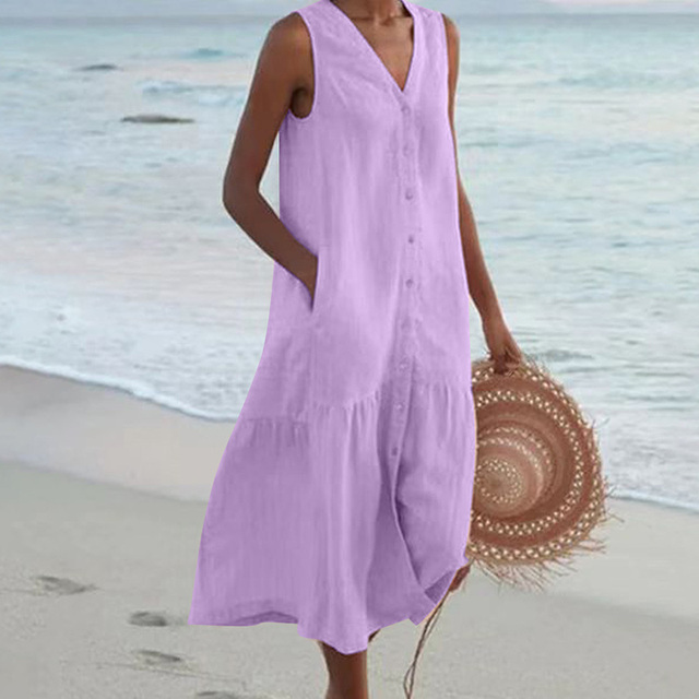 Robe d'été violette sans manches sur une femme à la plage, tenant un chapeau de paille. Mode estivale, tenue décontractée bord de mer.