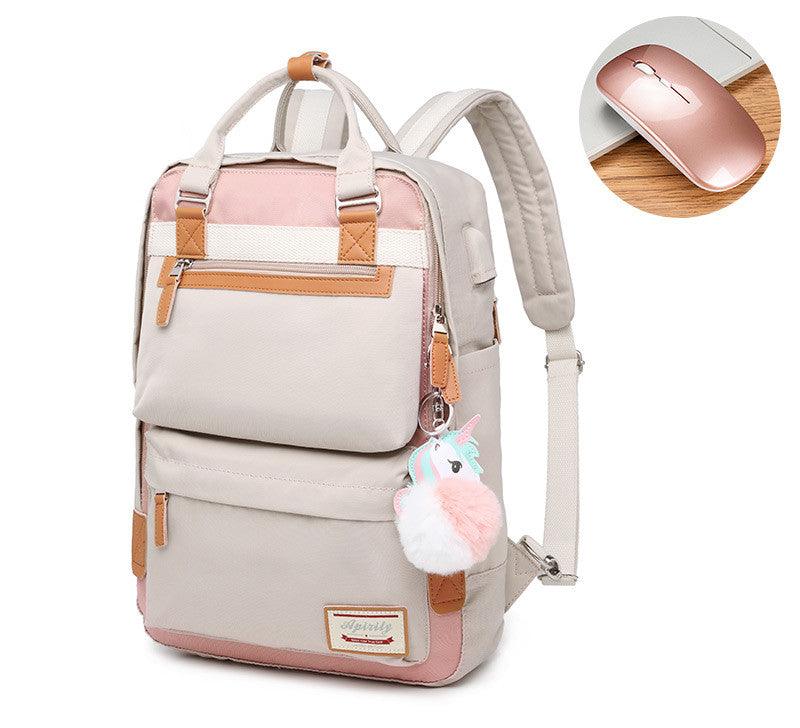 Sac à dos beige et rose avec pompon licorne, poches multiples, détails en cuir marron, accompagné d'une souris sans fil rose sur fond en bois.