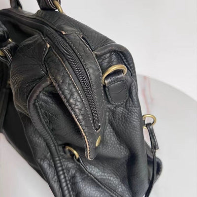 Sac à main en cuir noir texturé avec fermetures éclair dorées, design élégant et moderne, idéal pour la mode féminine et les accessoires tendance.