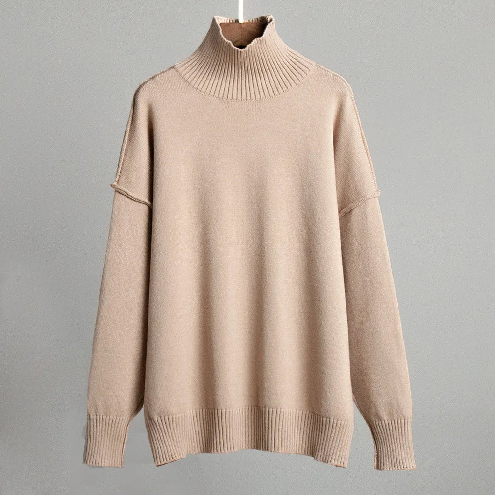 Pull-over beige à col roulé, manches longues, en laine douce, suspendu sur fond gris. Mode automne-hiver, vêtement chaud et élégant.