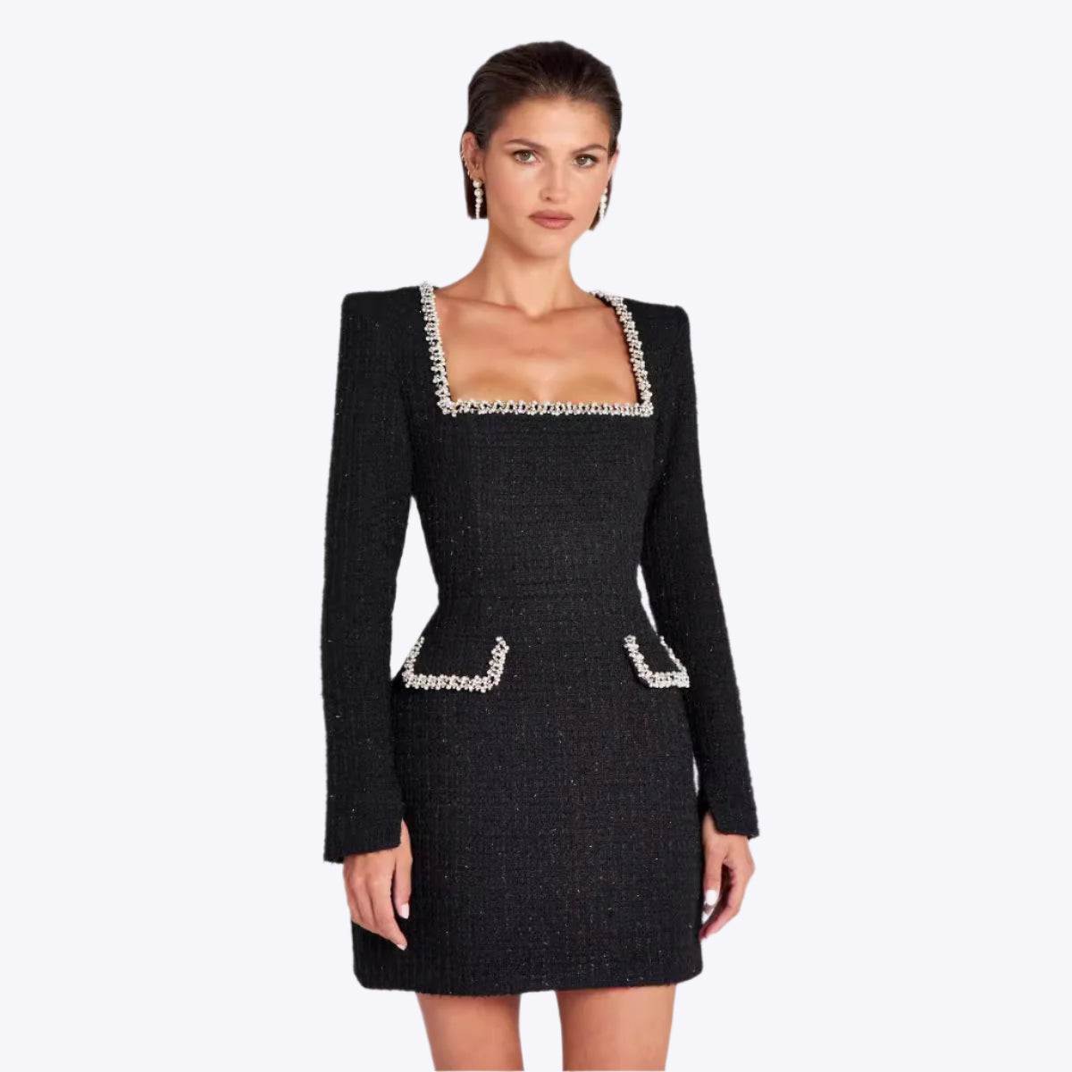 Robe noire élégante à manches longues, col carré orné de perles, poches avant, portée par une femme. Mode chic, tendance automne-hiver.