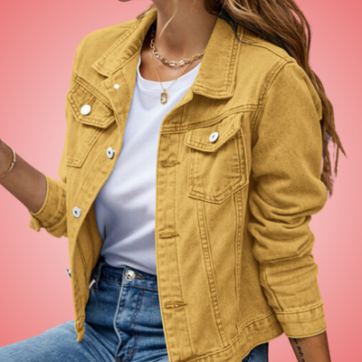 Veste en jean jaune pour femme, portée avec un t-shirt blanc et un jean bleu, sur fond rose. Mode féminine tendance, style décontracté.