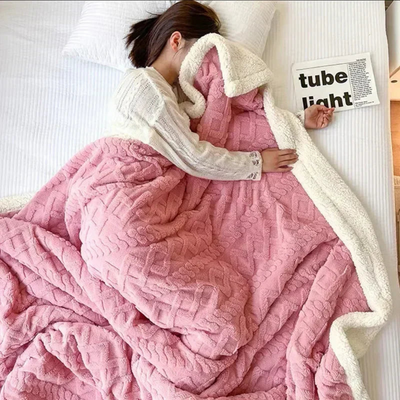 Femme endormie sous une couverture rose en peluche sur un lit blanc, lisant un magazine. Confort, détente, literie douce, chambre moderne.