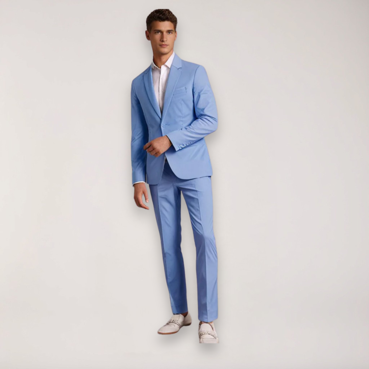 Homme en costume bleu clair élégant, chemise blanche, chaussures blanches, pose debout. Mode masculine, tenue formelle, style moderne.