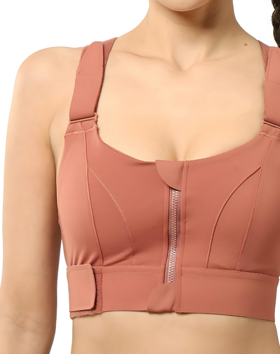 Femme portant une brassière de sport rose avec fermeture éclair avant et bretelles larges, idéale pour le fitness et le yoga.
