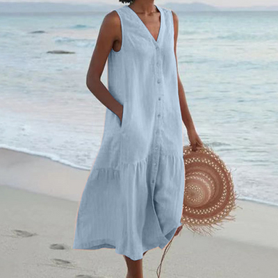 Robe d'été bleue sans manches sur une femme tenant un chapeau de paille, plage en arrière-plan. Mode plage, tenue estivale élégante.