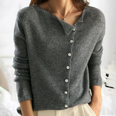 Femme portant un pull en laine gris avec boutons blancs, manches longues, col en V, style décontracté. Mode automne-hiver élégante et confortable.