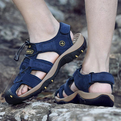 Sandales de randonnée bleues pour homme sur sentier rocheux, semelle antidérapante, confort optimal, parfaites pour activités extérieures et trekking.