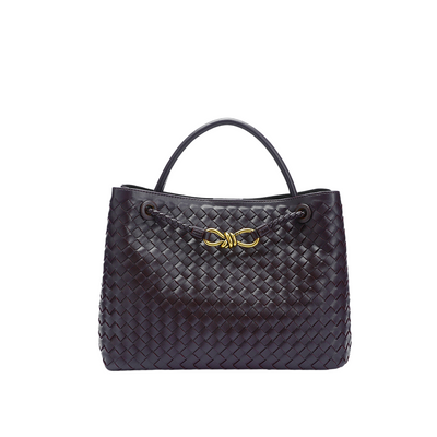 Sac à main en cuir tressé noir avec anse, orné d'un nœud doré. Accessoire de mode élégant et tendance pour femme.