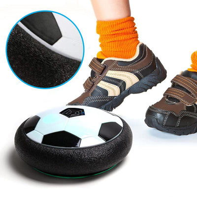 Chaussures d'enfant frappant un ballon de football flottant sur coussin d'air, gros plan sur la texture. Jouet interactif, jeu intérieur.