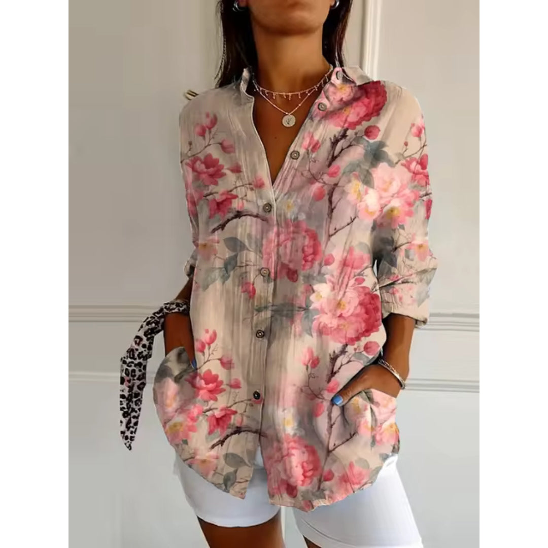 Chemisier femme à fleurs roses, manches longues, col ouvert, boutons, porté avec short blanc. Mode féminine, style décontracté, tendance printemps.