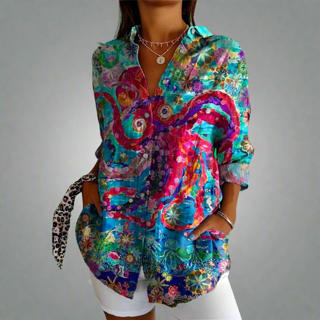 Chemise colorée femme avec motifs floraux et abstraits, manches longues, col ouvert, portée avec un pantalon blanc. Mode tendance, style bohème.
