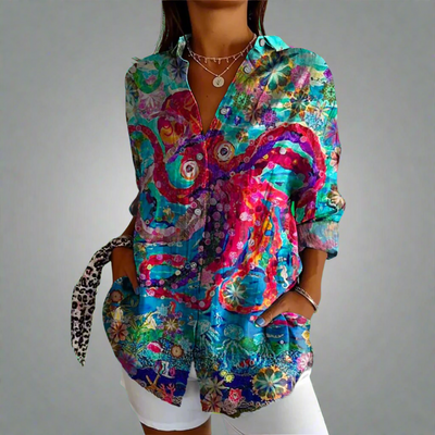 Chemise colorée femme avec motifs floraux et abstraits, manches longues, col ouvert, portée avec un pantalon blanc. Mode tendance, style bohème.