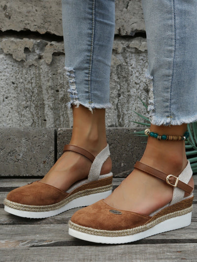 Sandales compensées marron en daim avec bride cheville, semelle en corde tressée, portées avec un jean déchiré. Mode estivale tendance.