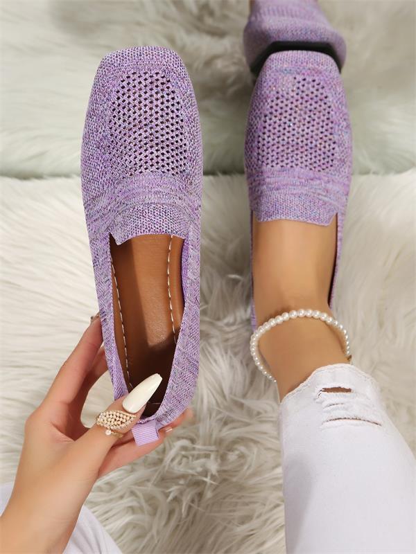Chaussures violettes en maille respirante portées par une personne avec un pantalon blanc déchiré, sur un tapis blanc moelleux.