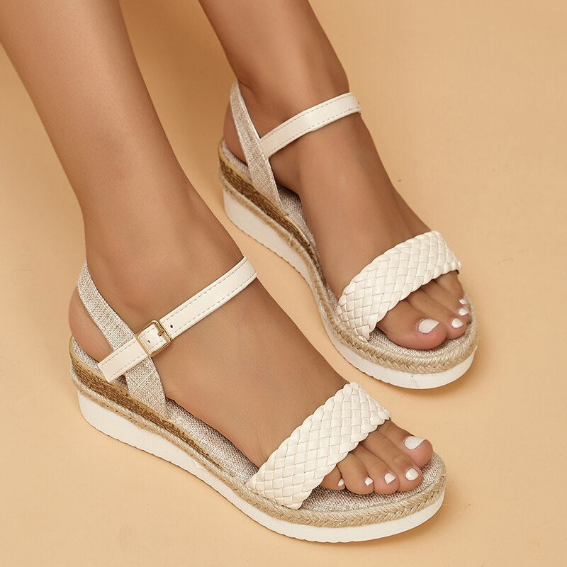 Sandales compensées blanches tressées pour femme, avec bride ajustable, sur fond beige. Chaussures d'été élégantes et confortables.