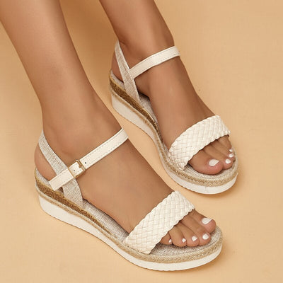 Sandales compensées blanches tressées pour femme, avec bride ajustable, sur fond beige. Chaussures d'été élégantes et confortables.