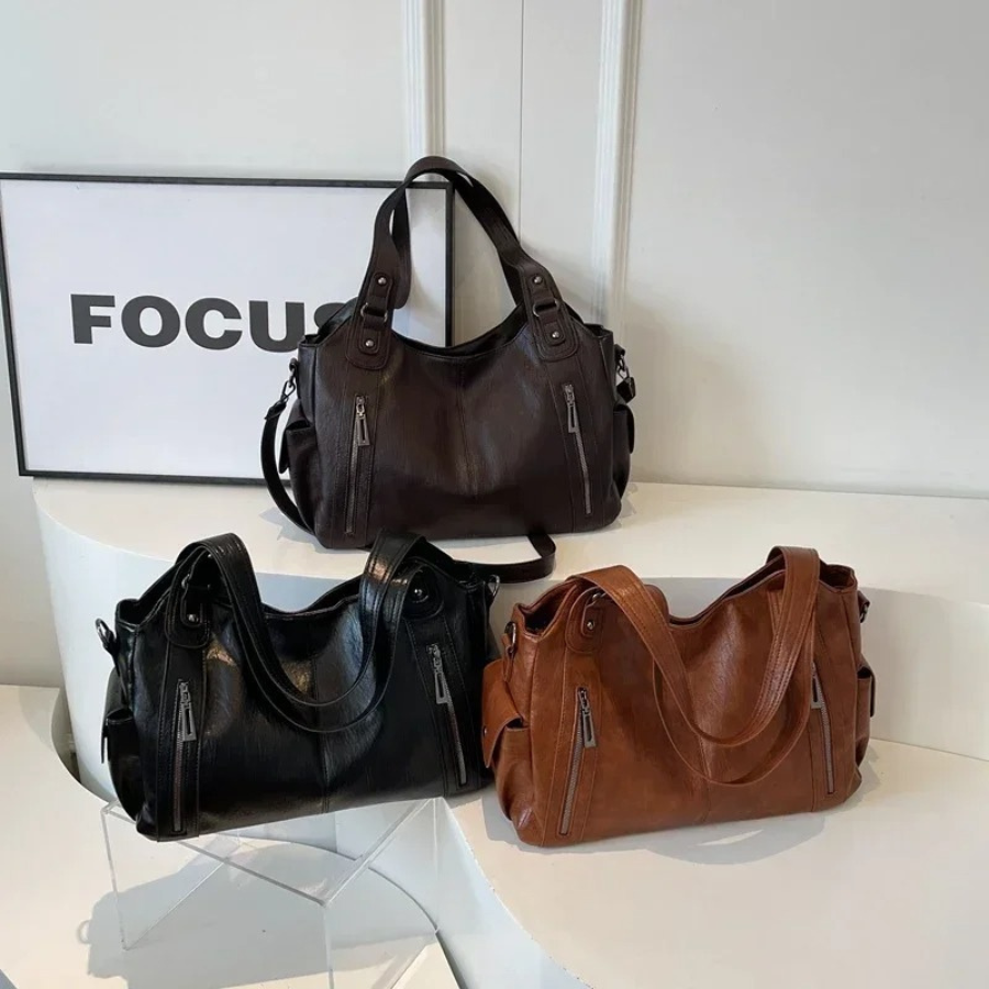 Trois sacs à main en cuir noir, marron et brun posés sur une table blanche, avec un cadre "FOCUS" en arrière-plan. Mode, accessoires, élégance.