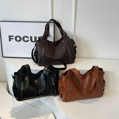 Trois sacs à main en cuir noir, marron et brun posés sur une table blanche, avec un cadre "FOCUS" en arrière-plan. Mode, accessoires, élégance.