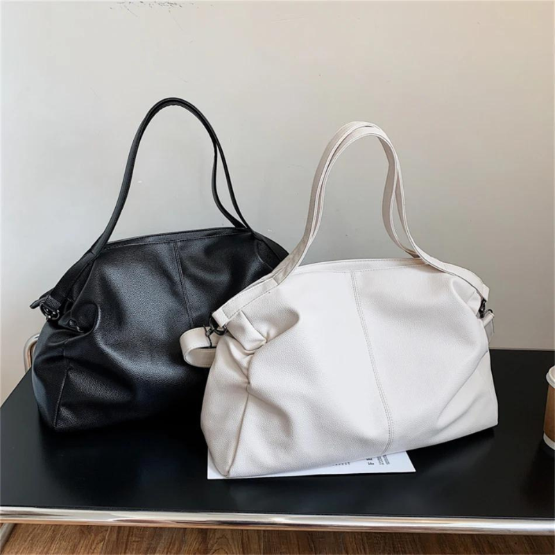 Deux sacs à main en cuir, un noir et un blanc, posés sur une table noire. Accessoires de mode élégants pour femmes, parfaits pour le quotidien.