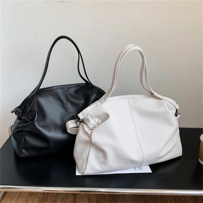 Deux sacs à main en cuir, un noir et un blanc, posés sur une table noire. Accessoires de mode élégants pour femmes, parfaits pour le quotidien.