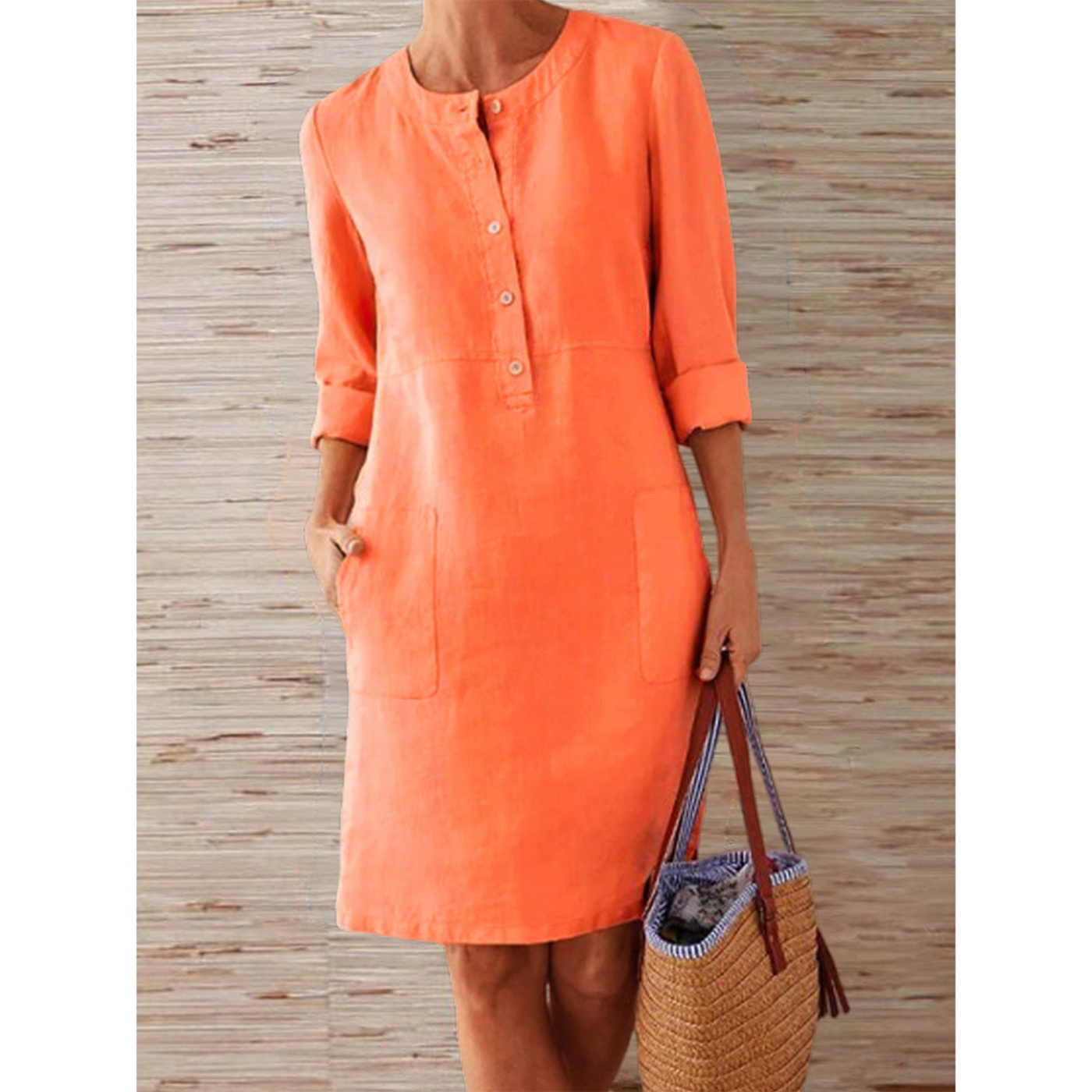 Robe orange en lin à manches trois-quarts, boutons sur le devant, poches latérales, tenue d'été décontractée, fond en bois clair.