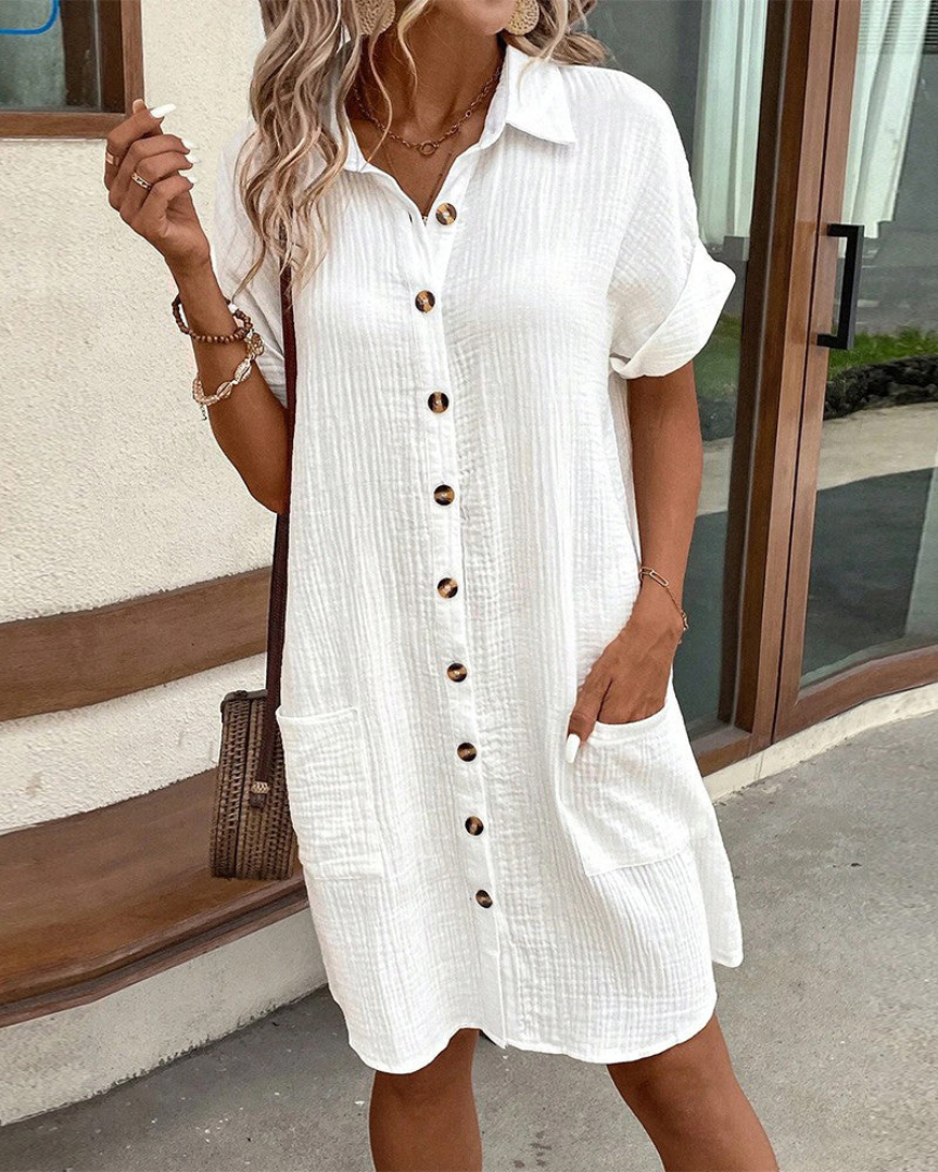 Robe chemise blanche en coton avec boutons en bois, manches courtes, poches avant. Mode estivale décontractée pour femme, style chic et confortable.