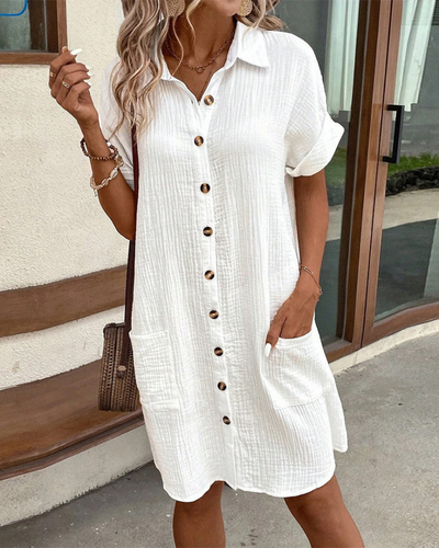 Robe chemise blanche en coton avec boutons en bois, manches courtes, poches avant. Mode estivale décontractée pour femme, style chic et confortable.