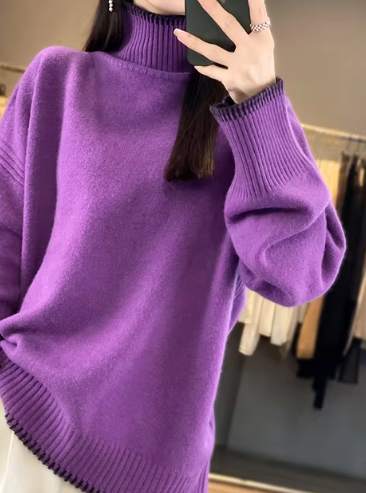 Femme portant un pull violet ample à col roulé, manches longues, dans un magasin de vêtements. Mode automne-hiver, style décontracté et élégant.