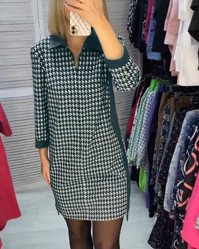 Robe à motif pied-de-poule noir et blanc, manches longues, portée par une femme dans une boutique de vêtements. Mode féminine élégante et tendance.