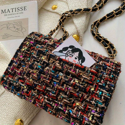 Sac à main en tweed multicolore avec chaîne dorée, posé sur un manteau blanc texturé. Livret "Matisse" et illustration insérés dans le sac.