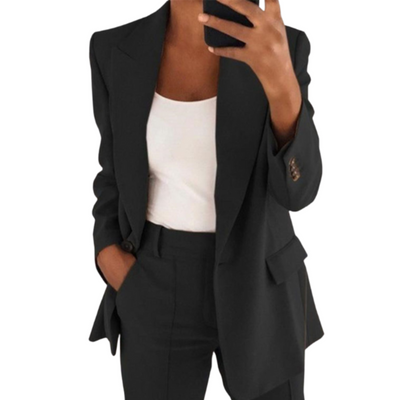 Femme en costume noir élégant, tenant un smartphone, portant un débardeur blanc. Mode professionnelle, tenue chic, style moderne.