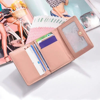 Portefeuille rose ouvert avec cartes de crédit et billets, posé sur une table blanche, magazines en arrière-plan. Accessoire mode pratique et élégant.