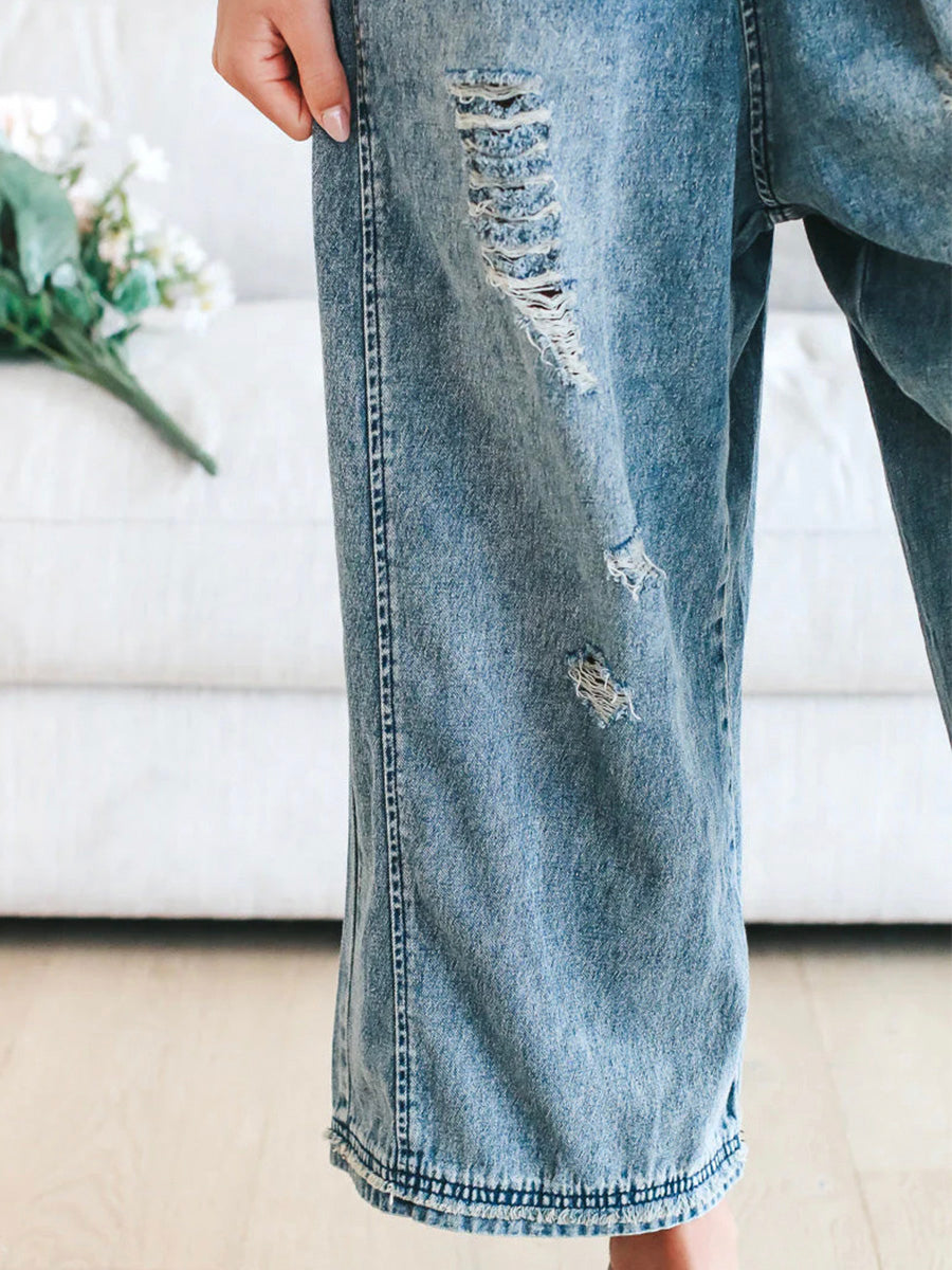 Jean déchiré tendance en denim bleu clair, style décontracté, avec fleurs en arrière-plan. Mode urbaine, look moderne et casual.